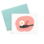 Letterpress greeting card with a cute fried egg and a piece of bacon jumping out of a skillet that says Best Friends all on a peachy circle background