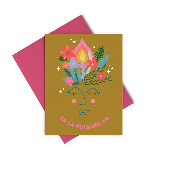 A dark mustard yellow greeting card with a face & festive plants/flowers with "fa la fucking la"