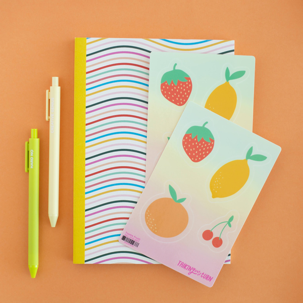 A sticker set with strawberries, lemons, oranges, and cherries. Displayed with Jotters and a notebook.