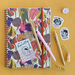 colorful leafy patterned spiral bound notebook with pens, pins and stickers