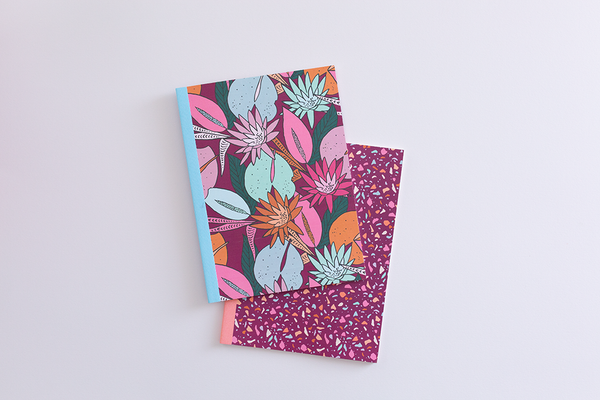Floral nights notebook on top of a Terrazzo speckled notebook with magenta background.