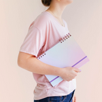 girl holding a purplish blue gradient colored journal under her arm