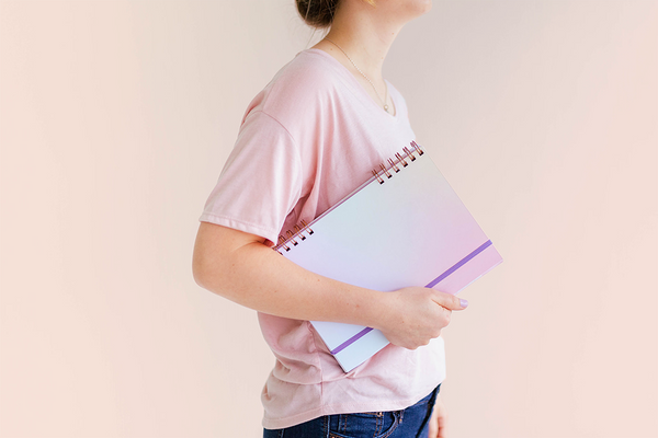 girl holding a purplish blue gradient colored journal under her arm
