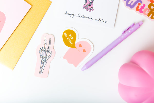 Halloween individual non-packaged sticker variations;  light pink sticker with skeleton hand peace sign; pink ghost sticker with heart eyes and mustard yellow gold text bubble saying "boo, you Whore."
