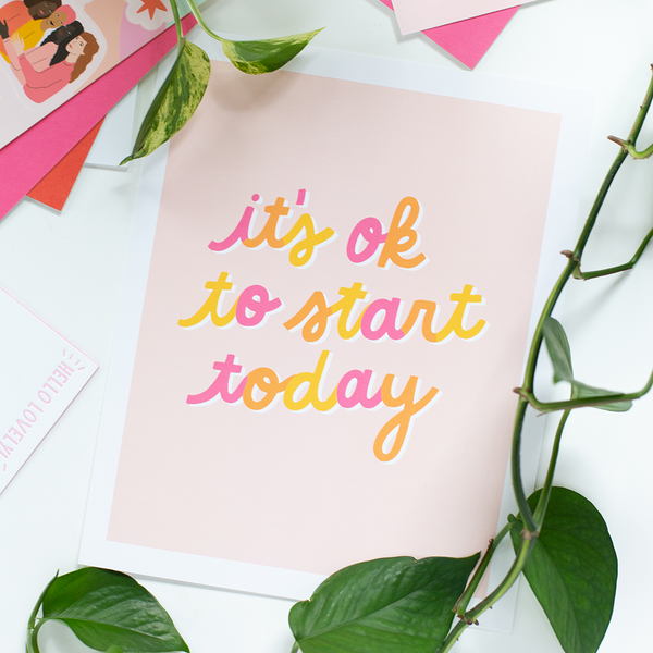 An "It's ok to start today," print with multicolored cursive lettering and a orange pastel background.