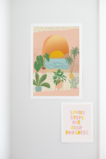 A print with window looking out at an ocean sunset. Before the window, different potter plants are on a cute floor. Print is multicolored and is hanging on a white wall along with a "Small Steps are also Progress" print hanging beneath it.