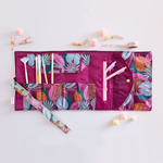 A multicolored jewel-toned, floral TOOTsie Roll roll-up bag. Bag is in Large and is good for holding stationary and/or cosmetic tools.