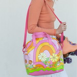 A skate bag with rainbow arches, abstract lines, and a variety of flowers. Designs are in pink, yellow, and green tones. Bag is being held by a person with orange roller skates.