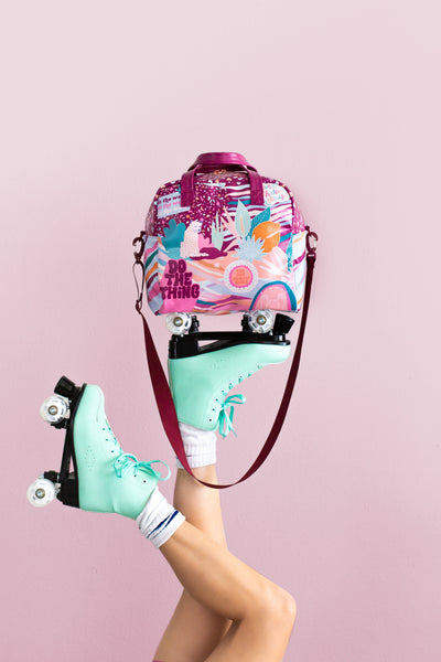 Multicolored Skate bag with terrazzo print and plant designs held up by someone's foot, they are wearing mint colored roller skates and white socks.