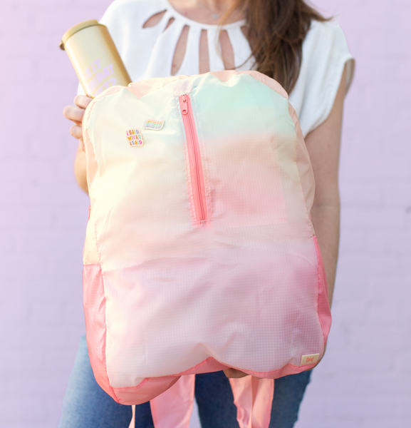 Person holding pastel ombre ripstop backpack putting a beverage into it.