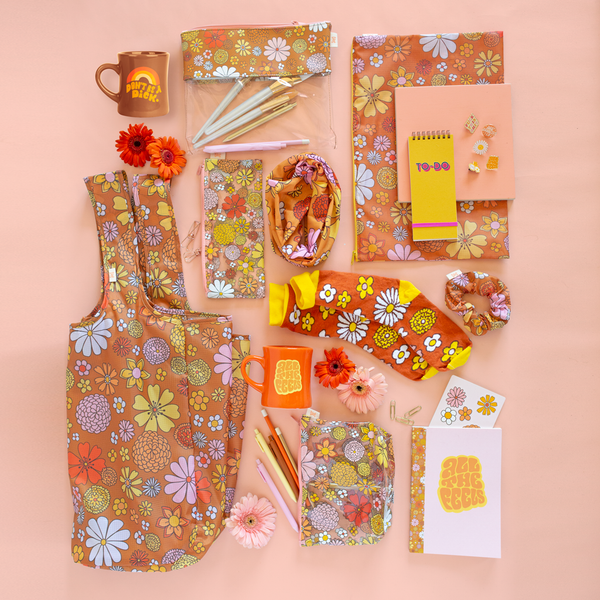 Collection of floral printed pouches, coffee mugs, notebooks, pins and socks laid out
