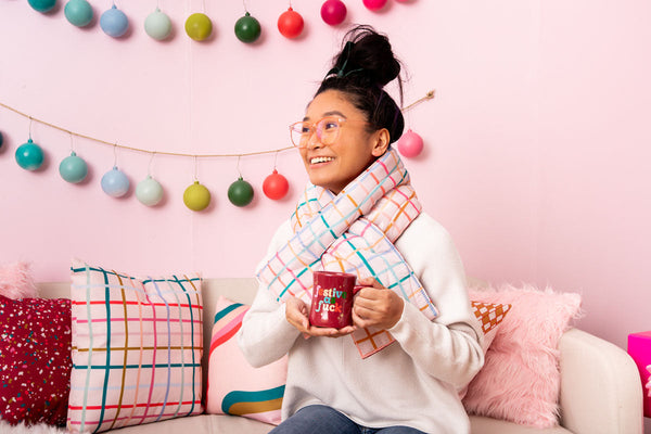 Red mug that says "festive as fuck" in colored letters with TOOT pillows and scarf.
