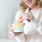 a girl dipping a cookie in a mug of milk that says shit. fuck. damn. in coral, yellow, and light blue