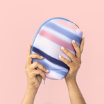 Hands holding a pink, peach, blue and navy striped pouch