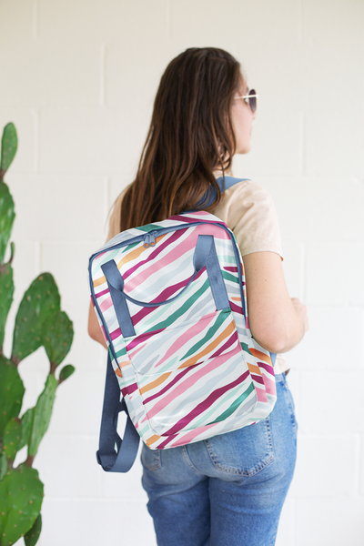 Lady holding colorful striped everyday backpack over her shoulder. 