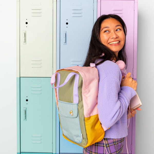 Girl wearing the multi color everyday backpack. Patel color lockers in the background. 
