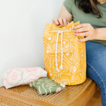 Woman in olive green shirt and jeans sitting next to a golden yellow bucket bag zen ladies talking out of turn