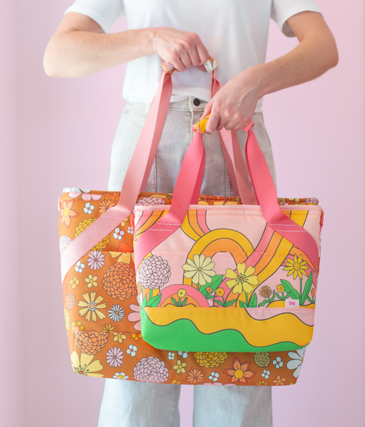 girl holding small and large cooler bags both with different groovy floral prints