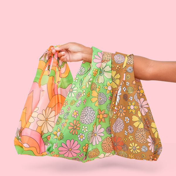 three floral printed tote bags, two over girls wrist and holding one in hand