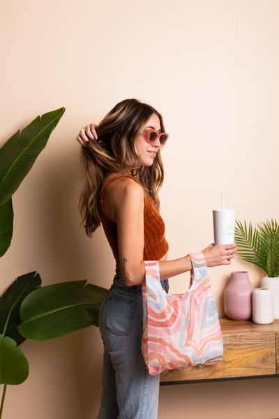 Woman holding multi-colored Go With the Flow Reusable bag with Cold Cup 