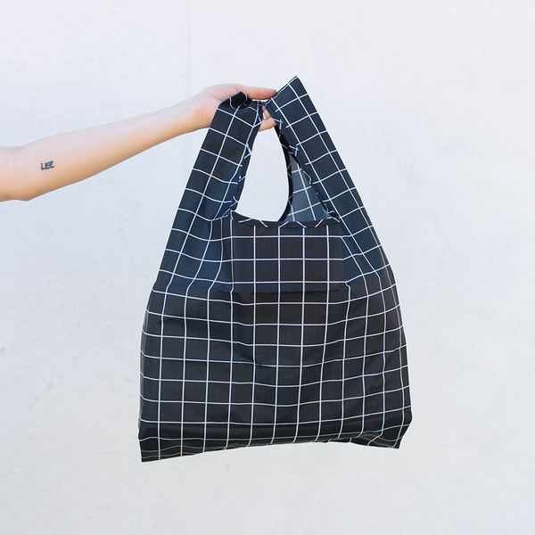 Image of a woman's hand holding a black and white grid pattern tote bag