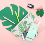 Cute pencil pouch lying on a monstera leaf with pens, car keys, and a Make It Happen taskpad.