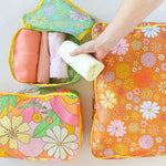 flower power packing cube set talking out of turn. small, medium, and large packing cube set which folds into a pouch. All with floral prints, one with green, one pink, and one brown.