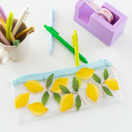A clear pixie pouch with lemons printed all over the pouch. Three Jotter pens included as well in the colors Grass Green, Citron Green, and Powder Blue. Displayed with a lilac Desk Set and Jotter Pens.