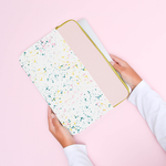 Hands holding a pink splatter laptop sleeve.