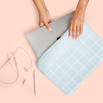 Girl's hand pulling a macbook out of a cute laptop sleeve in denim grid pattern.