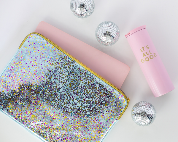 A confetti laptop sleeve sits with pink laptop and pink thermal drink ware. 