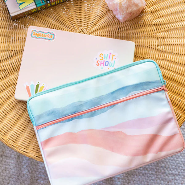 15in Zippered laptop sleeve with zippered front pocket and an open pocket in the back, laptop sleeve has water color stripes reminiscent of the sunset.A 15in laptop is wedge in the main caddy of the sleeve.