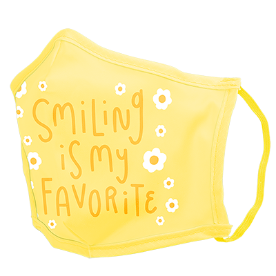 A yellow facemask with white daisies and yellow script saying "smiling is my favorite."