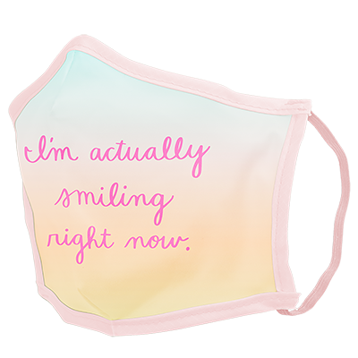 A pastel ombre facemask with pink cursive script saying "I'm actually smiling right now." 