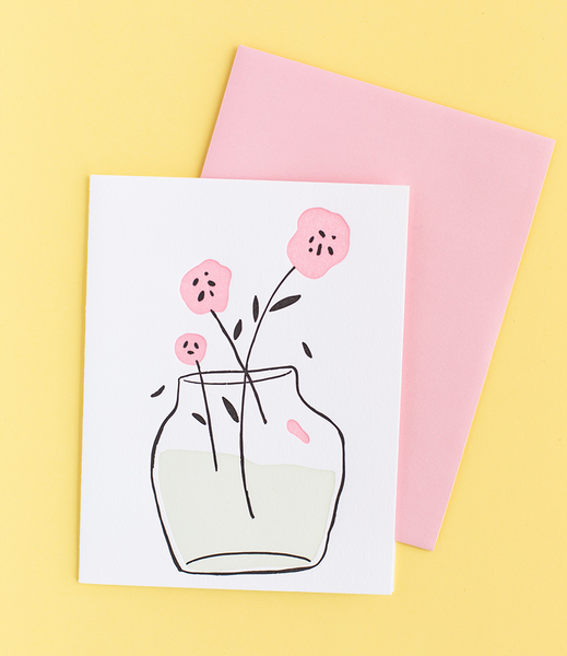 White greeting card with a flower vase containing three pink flowers. 