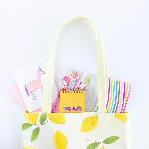 Cute tote bag with pastel background and yellow lemons pattern with various toot products inside