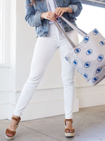 Woman in white jeans swinging a canvas tote bag in light gray with eyeballs pattern.