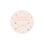 A circle sticker with the phrase "Sorry Our Zodiacs Just Aren't Compatible." A constellation in underneath the phrase and multicolored stars are scattered around the sticker.