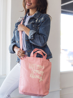Smiling brunette girl wearing a cute crossbody tote in peach canvas with Hot Mess Coming Through design..