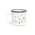 A white campfire mug in terrazzo pattern with muted specks of color in browns, mint, taupe, and mauve spread all around the mug.