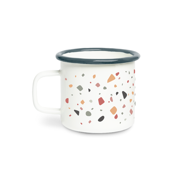 A white campfire mug in terrazzo pattern with muted specks of color in browns, mint, taupe, and mauve spread all around the mug.