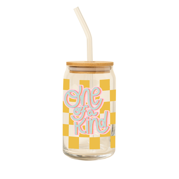 A 16 oz can glass with a glass straw; yellow checker print wraps around the glass. "One of a Kind" is printed on the front in a blue font with pink outline.