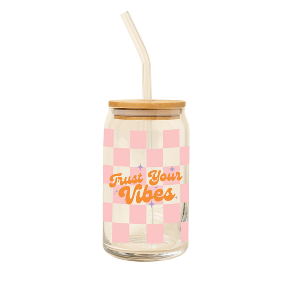 A 16 oz can glass with glass straw; pink checker print wrap around the glass. "Trust Your Vibes" is printed on the front in orange font, purple minimalist sparkle-stars surround the text.