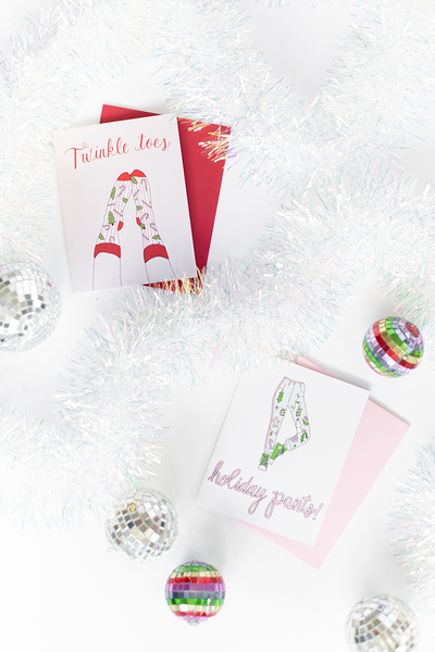 greeting cards 'twinkle toes' and 'holiday pants!' surrounded by tinsel.