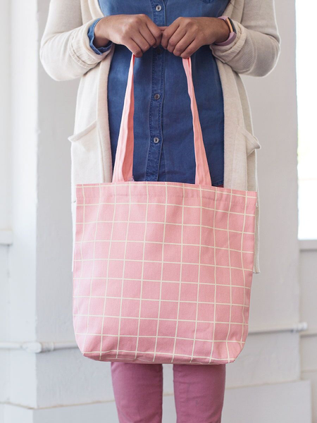 Girl holding a cute tote bag in peach canvas with yellow grid pattern.