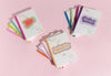 Assortment of colorful astrology themed note books in three spiral stacks.