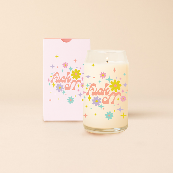 Can glass candle with text that reads "fuck off" in orange font, text is surrounded by bright, multi-color flowers and minimalist sparkle-stars. Box packaging with the same design sits behind candle.