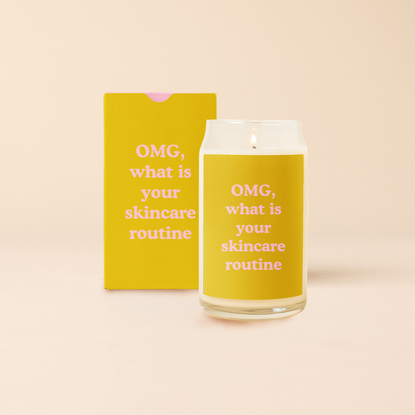 16 oz candle can glass with mustard yellow decal and text that reads "OMG, what is your skincare routine" in pink font. Mustard yellow box with same design sits behind candle.