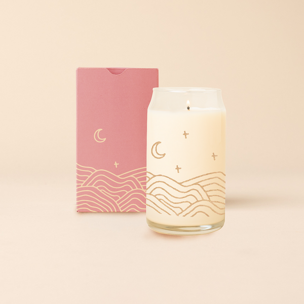 Rocks glass candle with flowing hills, moon and star design. Blush box packaging with same design as candle. 