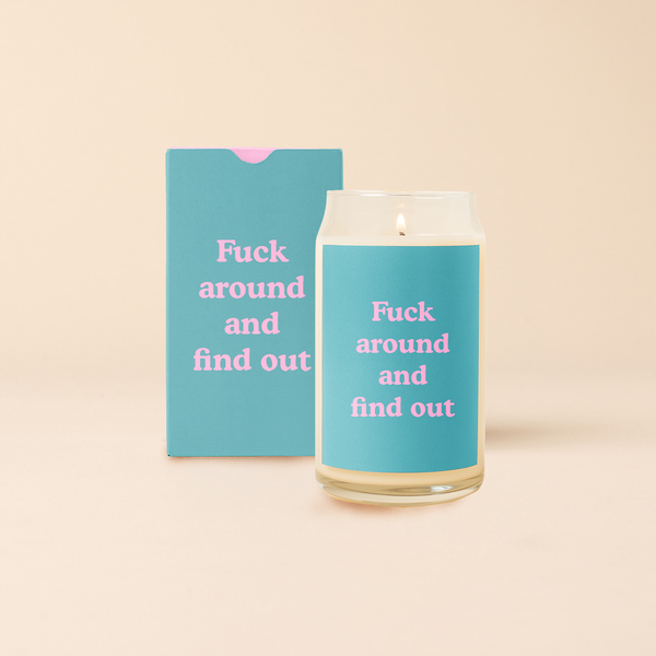 16 oz candle can glass with teal decal and text that reads "Fuck around and find out" in pink font. Teal box with same design sits behind candle.